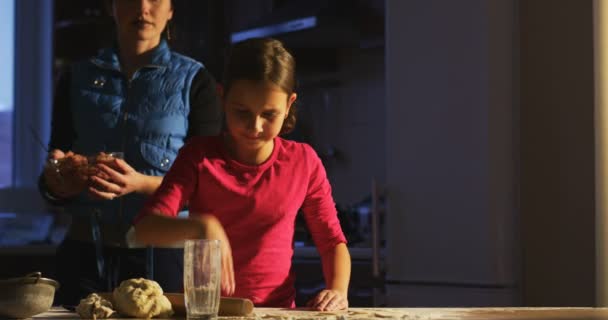 小さなシェフの調理を学んで 家族との夕食の準備を学習の母を調理する準備ができてテーブルに小さな女の子 — ストック動画