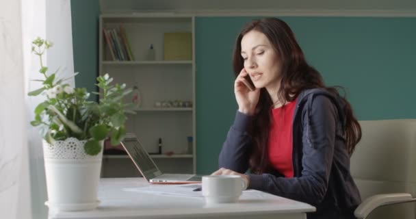 有吸引力的褐发女郎妇女自由职业者工作从家庭计算机和交谈的电话高兴成功与销售 — 图库视频影像