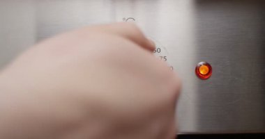 Sıcaklık topuzu erkek parmak üzerinde bir soba Closeup dönüm üzerinde kırmızı kamera vurdu