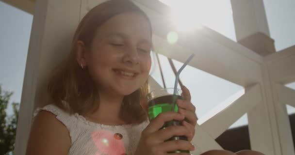 女孩喝茶点饮料与稻草坐在外面与太阳火焰 — 图库视频影像