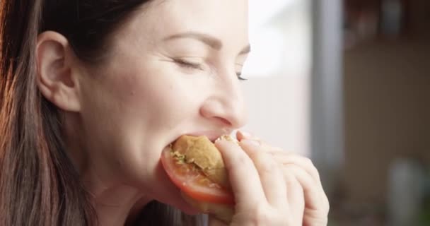 Красивая Женщина Ест Чизбургер Удовольствием Балуясь Вкусом Помещении Солнцем Сияние — стоковое видео