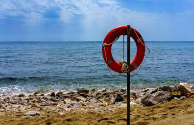 İspanyol plajında kırmızı kauçuk halka, mavi gökyüzünün altında kum.