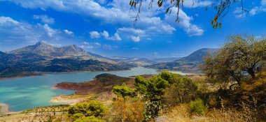 Endülüs 'teki dağları ve tepeleri yol çayırları ve çalıları olan turkuaz göl manzarası