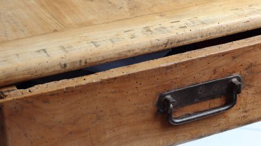 Çekmecede metal saplı eski, ahşap bir masa.