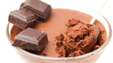 Şeffaf kase çikolatalı mus ve çay kaşığı ve beyaz arka planda izole edilmiş üç parça siyah çikolata.