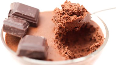 Şeffaf kase çikolatalı mus ve çay kaşığı ve beyaz arka planda izole edilmiş üç parça siyah çikolata.