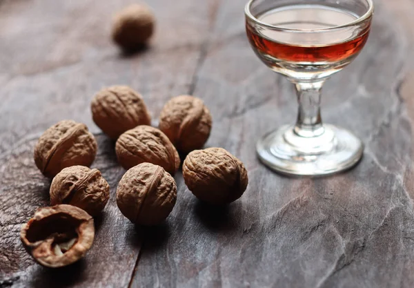 Walnut liquor in glass and walnuts on the old wooden background in backlight