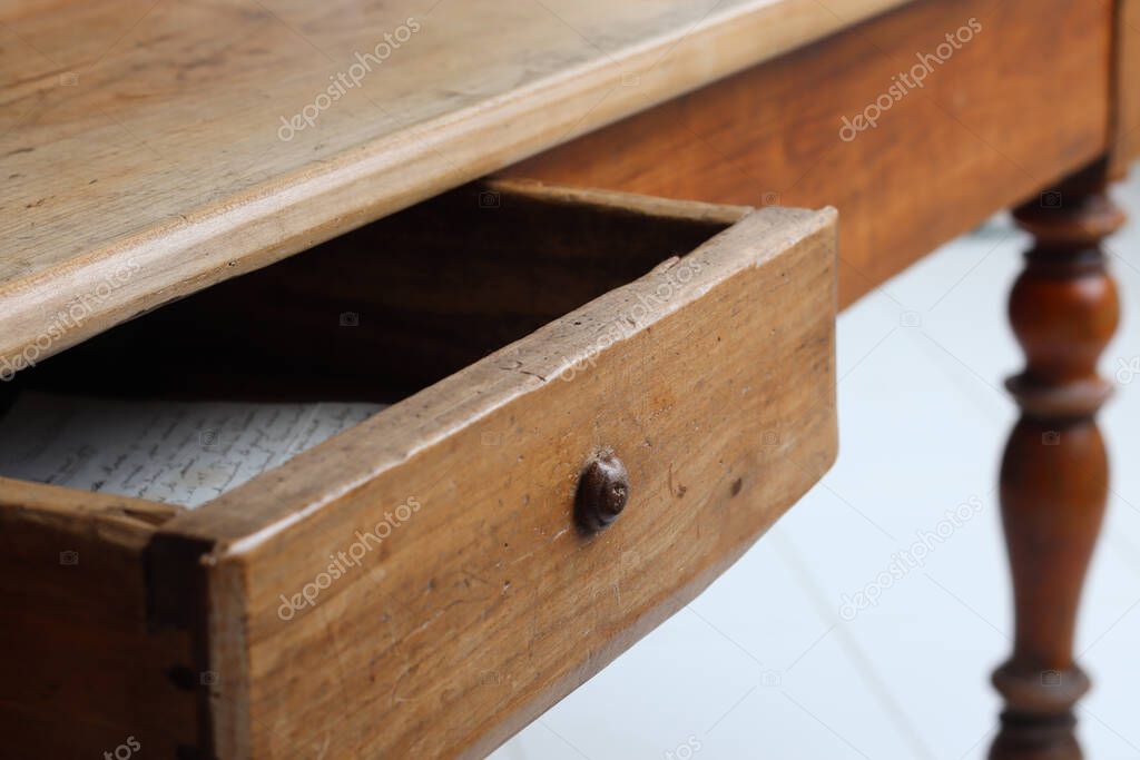 Old vintage wooden table with half-open drawer with a handwritten letter inside