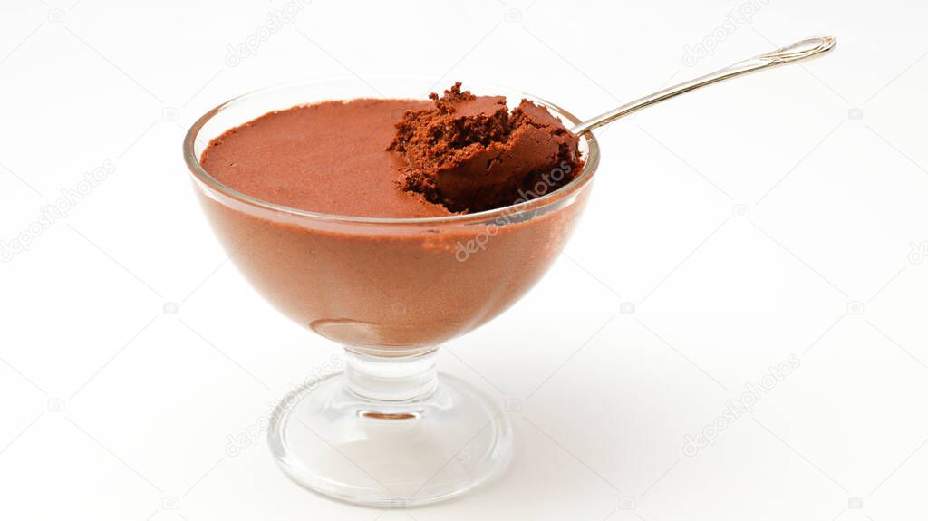 Transparent bowl with chocolate mousse and teaspoon isolated on a white background