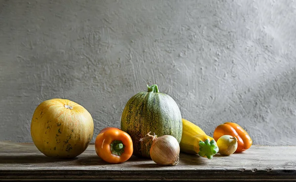 Organik taze sebzeler - sarı kabak, yuvarlak kabak, dolgun biber, gri arka planda soğan. Kopyalama alanı ile natürmort