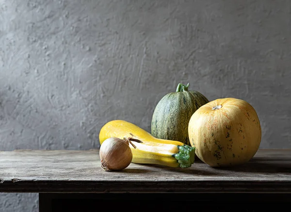 Organic fresh vegetables - yellow zucchini, round zucchini, bell peppers, onion on the gray background. Still life with copy space