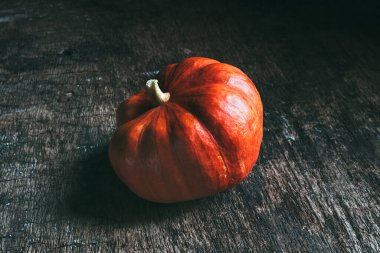 Koyu, ahşap bir zeminde izole edilmiş taze, olgun bir balkabağı. Hasat.