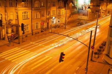 Geceleri bir şehir, araçların ışıklarının parlaklığı ve gölgelerinin dış hatlarıyla.