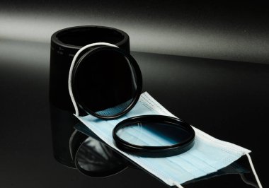 Mercek kaputu, yarım gri filtre ve hijyen maskesi var.