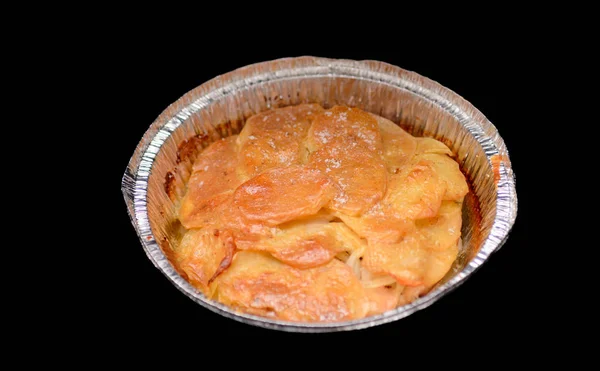 The baked potatoes sliced with cheese and onions on a baking sheet from a foil. Isolated on a black background.