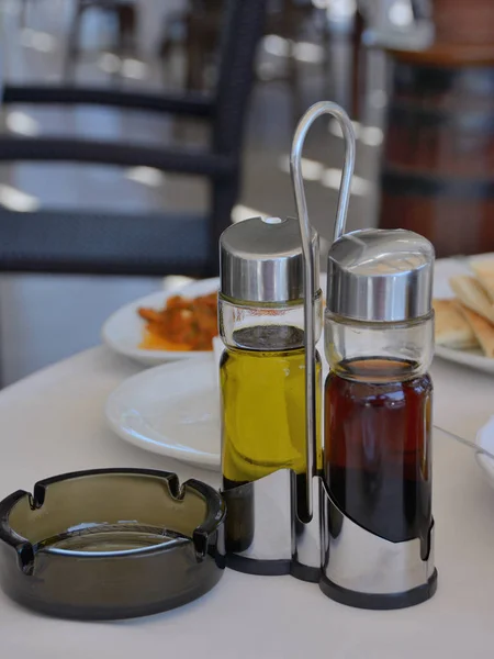 table in cafe served by small bottles with olive oil and balsam vinegar and a glass ashtray