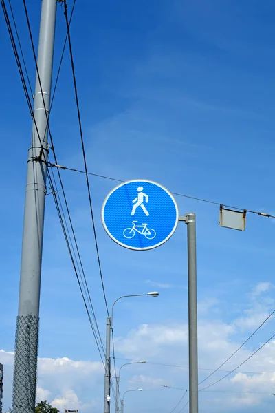 Road sign with reflective coating pedestrian and Bicycle path, against the background of blue sky and wires