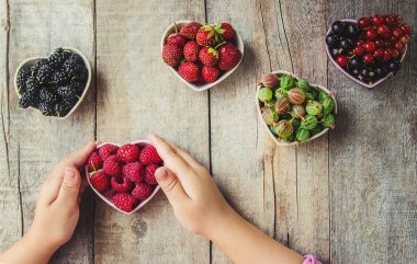 Çilek bir kalp şeklinde bir çocuğun elinde. Ev. Seçici odak.
