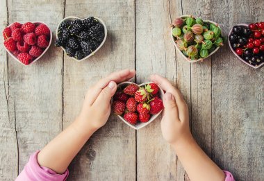 Çilek bir kalp şeklinde bir çocuğun elinde. Ev. Seçici odak.