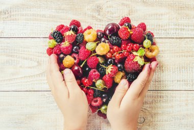 Çilek bir kalp şeklinde bir çocuğun elinde. Ev. Seçici odak.