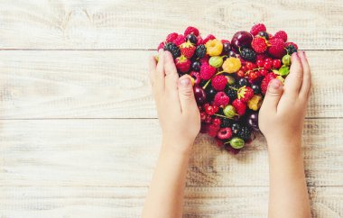 Çilek bir kalp şeklinde bir çocuğun elinde. Ev. Seçici odak.