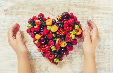 Çilek bir kalp şeklinde bir çocuğun elinde. Ev. Seçici odak.