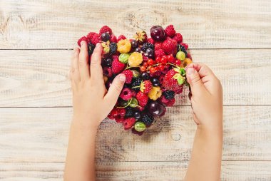 Çilek bir kalp şeklinde bir çocuğun elinde. Ev. Seçici odak.