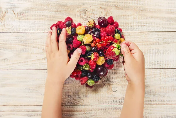 Çilek bir kalp şeklinde bir çocuğun elinde. Ev. Seçici odak.