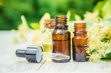 Ihlamur özü ve küçük bir şişe içinde çiçekler. Seçici odak.