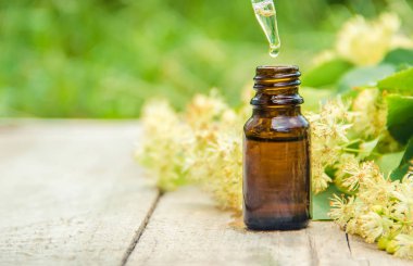 Ihlamur özü ve küçük bir şişe içinde çiçekler. Seçici odak.