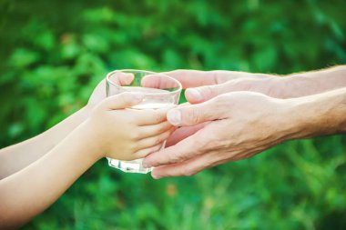 Baba çocuk bir bardak su verir. Seçici odak.