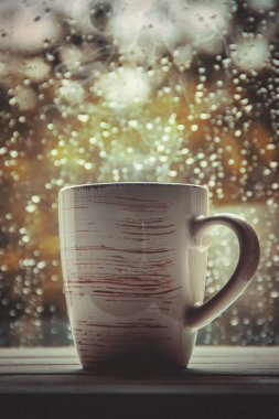 Bir fincan çay arka plan yağmurda pencerenin dışında. Seçici odak. 