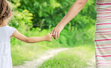 Anne ve kızı el ele tutuşarak yolda yürüyor. Seçici odak. Doğa.