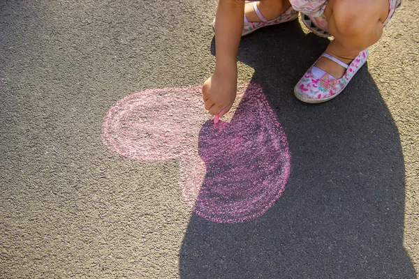 子供はアスファルトの心臓にチョークを塗ります 選択的フォーカス — ストック写真