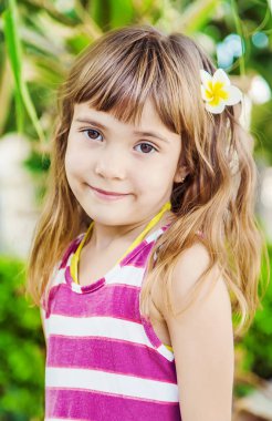 fon ve palmiye ağaçlarının karşı saçında plumeria çiçekli kız. Seçici odak. Doğa.