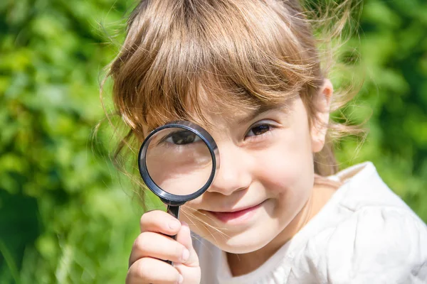 Das Kind schaut in ein Vergrößerungsglas. Zunahme. Selektiver Fokus. — Stockfoto