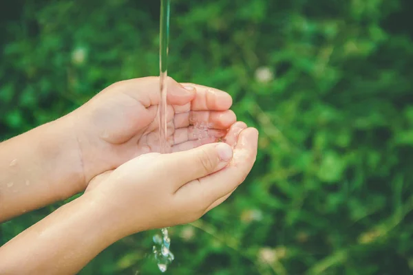 L'acqua scorre nelle mani del bambino. Focus selettivo . — Foto Stock