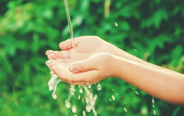 Water flows into the hands of the child. Selective focus. — Stock Photo, Image