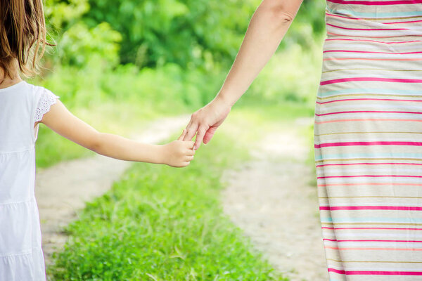 Мама и дочь идут по дороге держась за руки
.