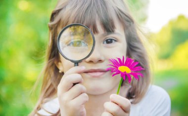 Çocuk bir büyüteç içine bakıyor. Arttır. seçici odak.