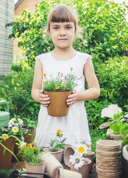 Une petite fille plante des fleurs. Le jeune jardinier. Concentration sélective. — Photo