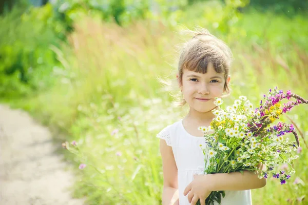 Niño con un ramo de flores silvestres. Enfoque selectivo. naturaleza . — Foto de Stock