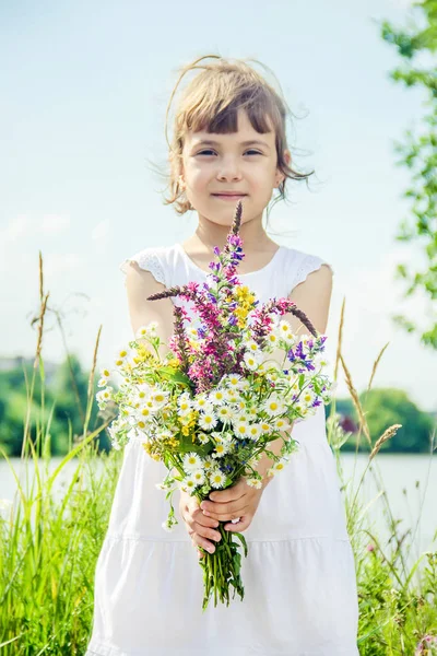 Niño con un ramo de flores silvestres. Enfoque selectivo. naturaleza . — Foto de Stock