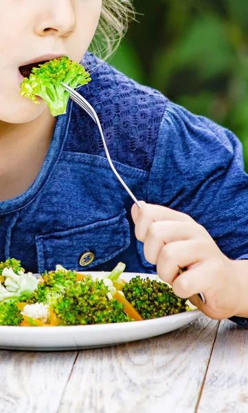 Child eats vegetables. Summer photo. Selective focus — Stock Photo, Image