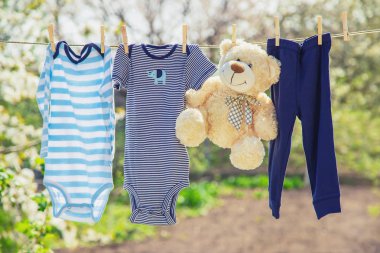 Bebek giysileri ve aksesuarları açık havada yıkandıktan sonra halat üzerinde tartMak. Seçici odaklama.