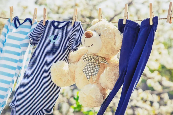 Dětské oděvy a příslušenství váží na lano po umytí v otevřeném vzduchu. Selektivní zaměření. — Stock fotografie