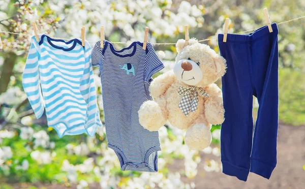 Babykläder och accessoarer väger på repet efter tvättning i det öppna luft. Selektivt fokus. — Stockfoto