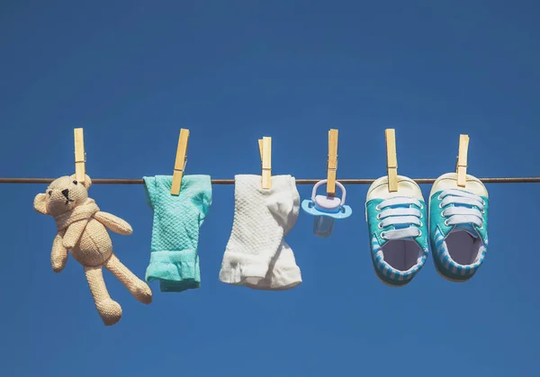 Babykläder och accessoarer väger på repet efter tvättning i det öppna luft. Selektivt fokus. — Stockfoto