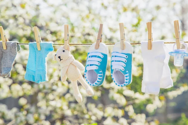 Babykläder och accessoarer väger på repet efter tvättning i det öppna luft. Selektivt fokus. — Stockfoto