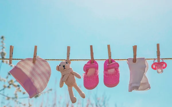 La ropa y los accesorios del bebé pesan sobre la cuerda después de lavarse al aire libre. Enfoque selectivo . —  Fotos de Stock